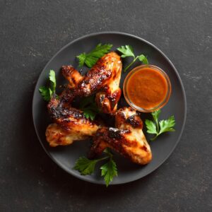 Crispy sauce-glazed chicken wings on a dark neutral background